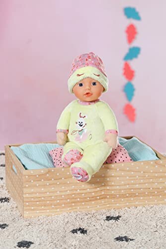 Poppenbaby in een houten doos met roze en blauwe achtergrond.