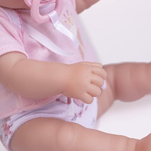 Babypop met roze fopspeen en kleding.