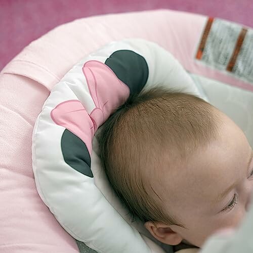 Baby in autostoeltje met roze kussen