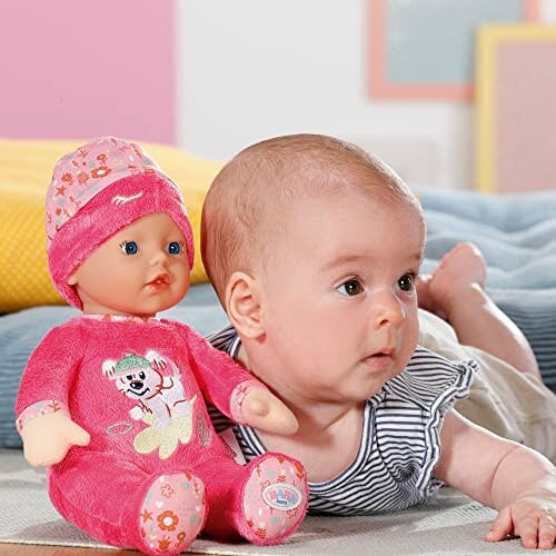 Baby ligt naast een pop in roze kleding.