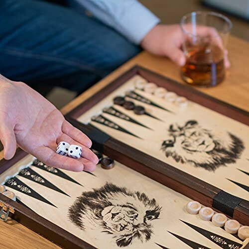 Persoon speelt backgammon met dobbelstenen en een drankje