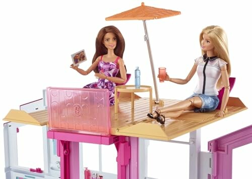 Twee Barbie-poppen op een dakterras met parasol