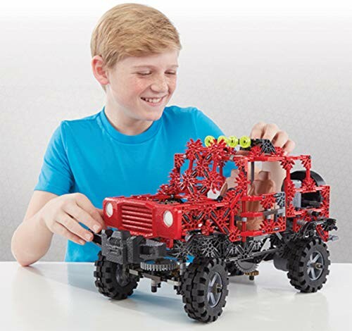 Jongen speelt met rode constructiespeelgoedtruck.