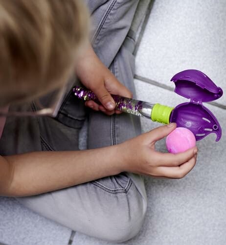 Kind speelt met een speelgoedstok en roze bal.