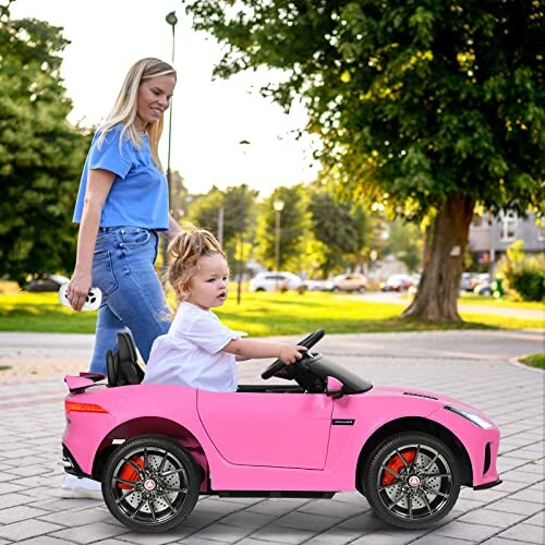 Kind in roze speelgoedauto met volwassene die duwt