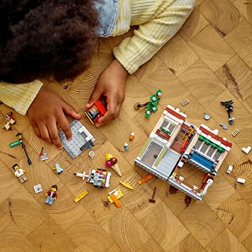 Kind speelt met Lego-set op houten vloer.