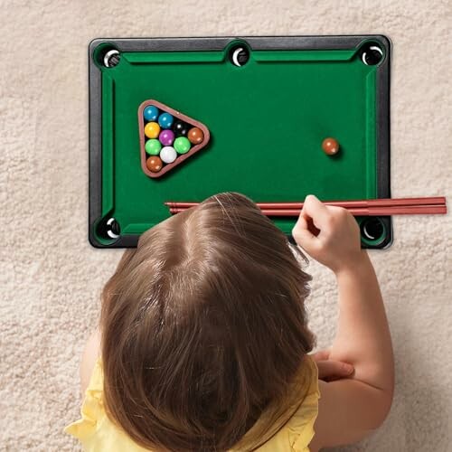 Kind speelt met mini pooltafel.