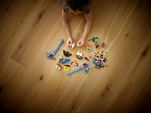 Kind speelt met LEGO-stenen op houten vloer.