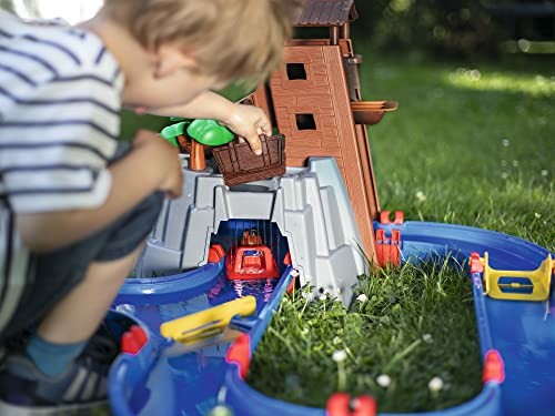 Kind speelt met watertafel in de tuin.