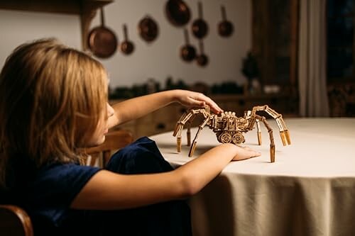 Kind speelt met houten speelgoedspin aan tafel.