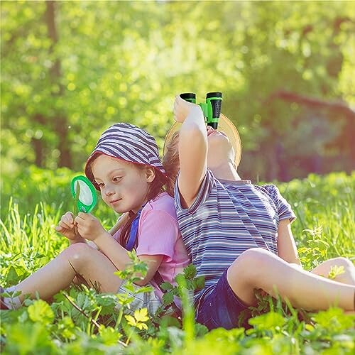 Kinderen spelen met een vergrootglas en verrekijker in het gras.