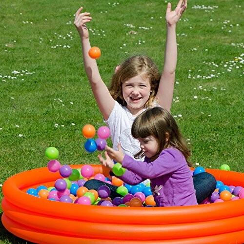 Kinderen spelen in een ballenbad in de tuin.