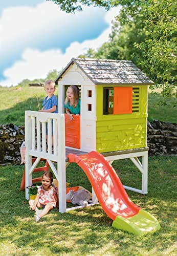 Kinderen spelen in een kleurrijk speelhuisje met glijbaan in de tuin.