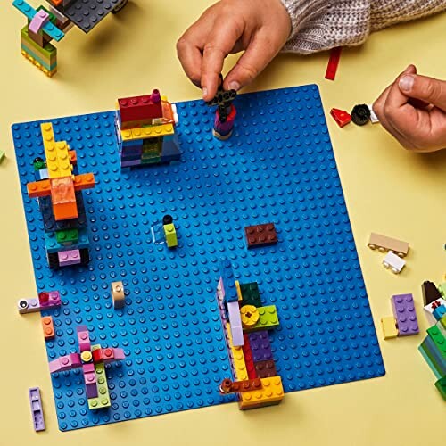 Kinderen spelen met Lego op blauwe basisplaat.