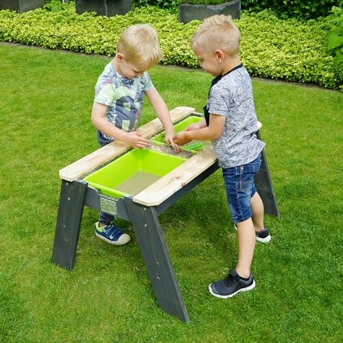 Twee kinderen spelen bij een zandtafel in de tuin.