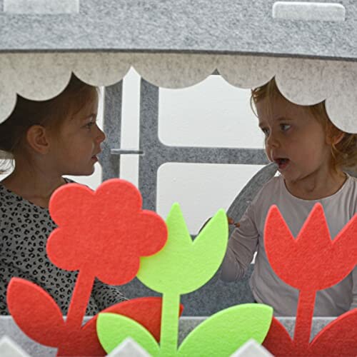 Twee kinderen spelen in een speelhut met vilten bloemen.