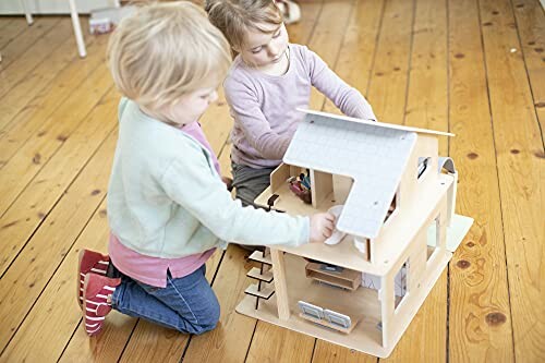 Kinderen spelen met een poppenhuis op houten vloer.