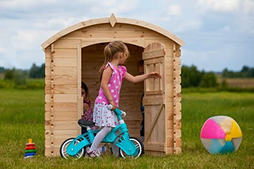 Kinderen spelen in houten speelhuisje met fiets en bal