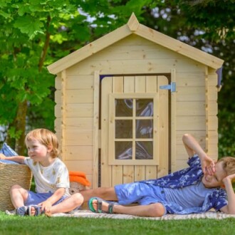 Kinderen spelen voor een houten speelhuisje in de tuin.