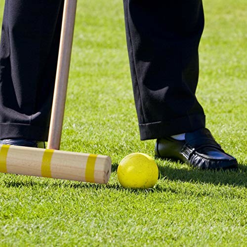 Voet naast croquetbal en mallet op grasveld