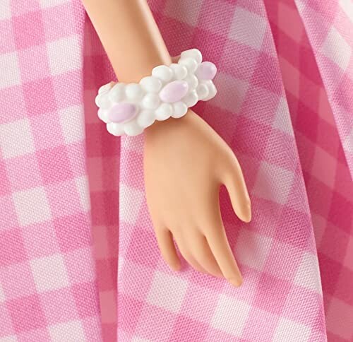 Poppenhand met witte en roze armband