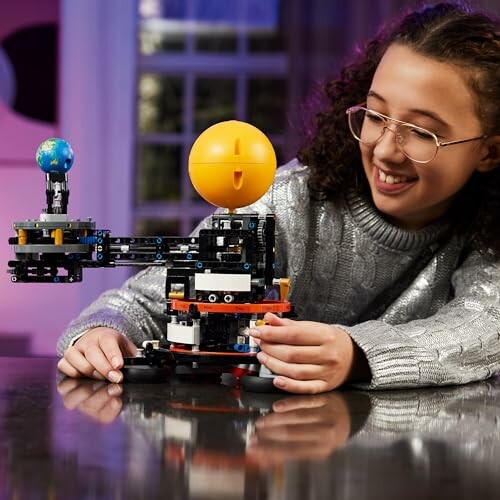 Meisje speelt met LEGO-model van zonnestelsel.