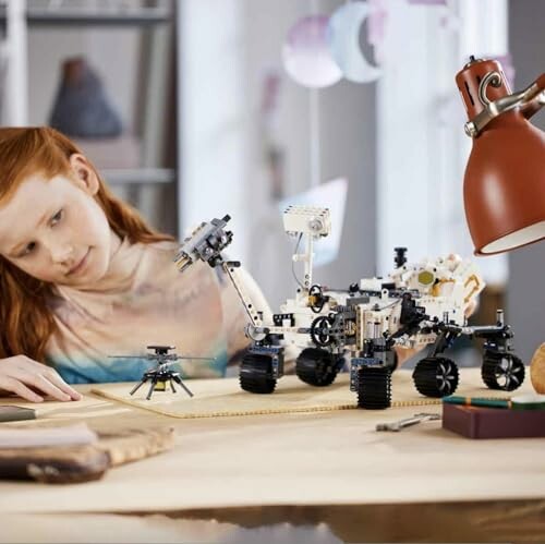 Meisje kijkt naar robotachtige rover op tafel.