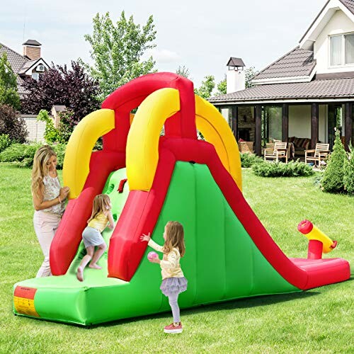 Kinderen spelen op een opblaasbare glijbaan in de tuin.