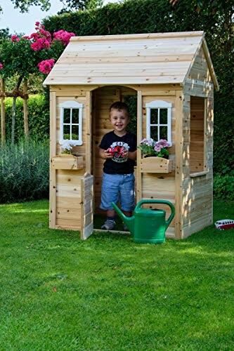 Kind speelt in houten speelhuisje in de tuin.