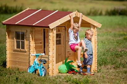 Kinderen spelen bij een houten speelhuisje in de tuin.