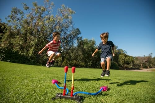 Kinderen springen over speelgoed in het gras