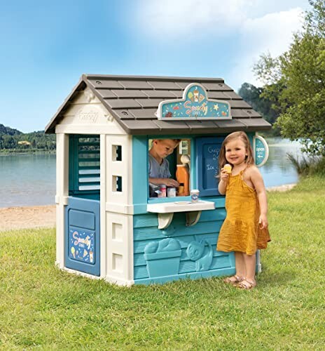 Kinderen spelen in een speelhuisje buiten bij het water.