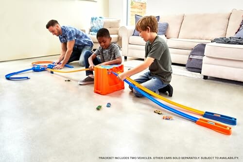 Kinderen spelen met een speelgoedautobaan in de woonkamer.