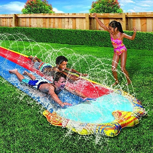 Kinderen spelen op een waterglijbaan in de tuin.