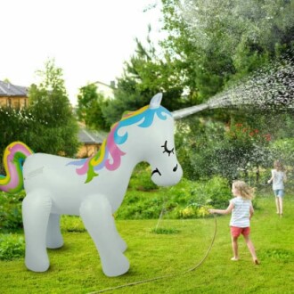 Kinderen spelen met een opblaasbare eenhoorn sproeier in de tuin.