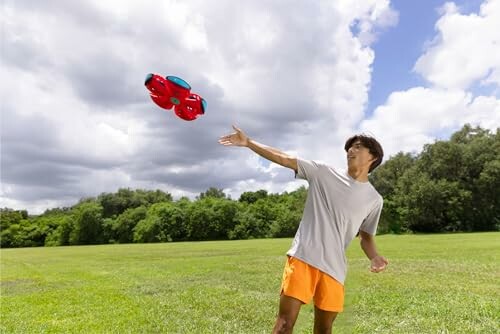 Man gooit een rode speelgoeddrone in een park