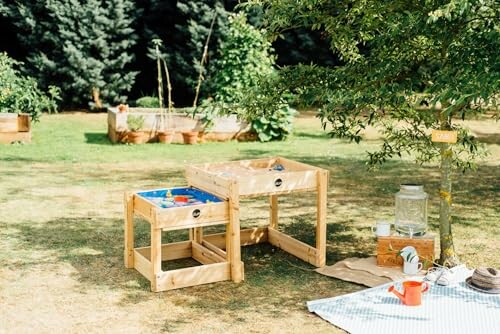 Tuin met houten speelstations en picknick op gras