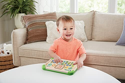 Peuter speelt met speelgoedtablet in woonkamer.